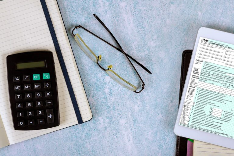 Calculatrice, lunettes et formulaire administratif posés sur un bureau