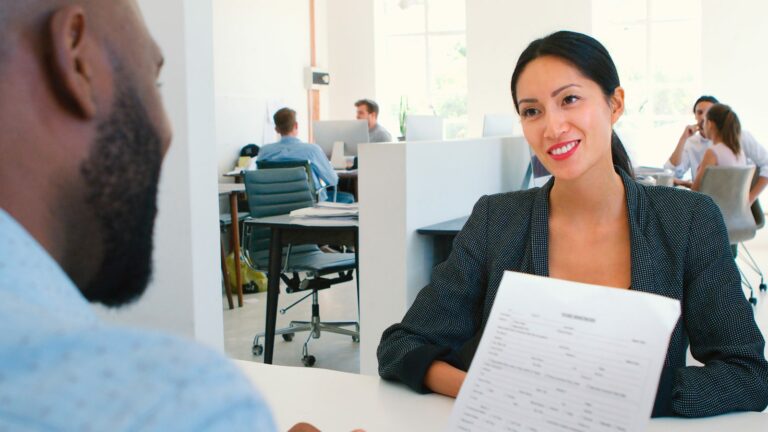 Entretien de recrutement dans un bureau ouvert, curriculum vitae à la main